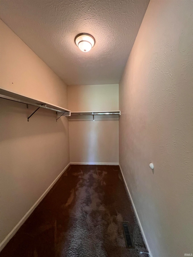 walk in closet with dark colored carpet