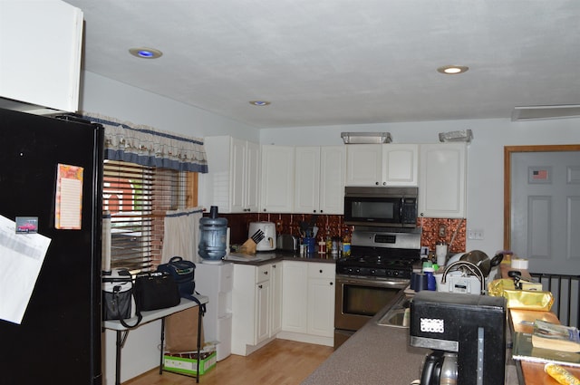 kitchen with tasteful backsplash, light hardwood / wood-style floors, white cabinetry, and black appliances