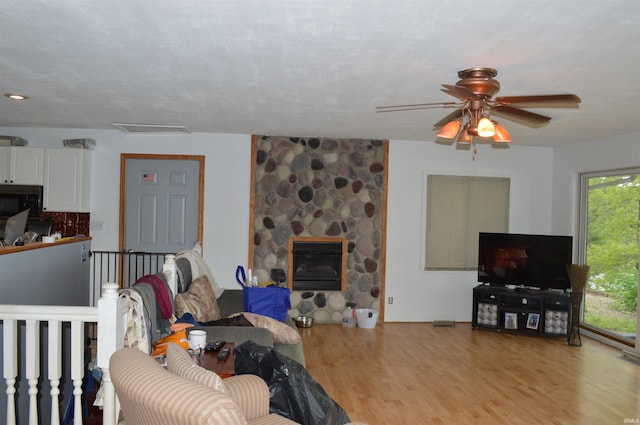 living room with a fireplace, light hardwood / wood-style flooring, and ceiling fan