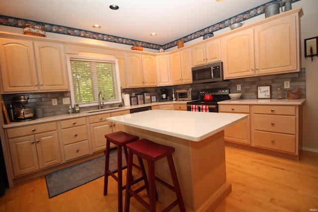 kitchen featuring sink, a center island, stainless steel appliances, and light wood-type flooring