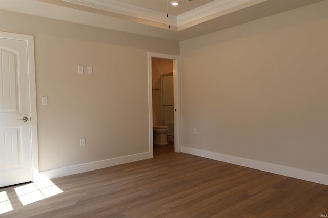 unfurnished room with a tray ceiling, wood-type flooring, and ornamental molding