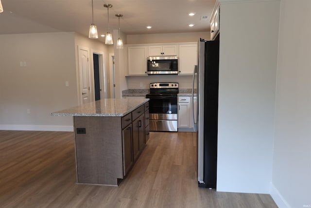 kitchen featuring decorative light fixtures, stainless steel appliances, a center island, white cabinets, and light hardwood / wood-style floors