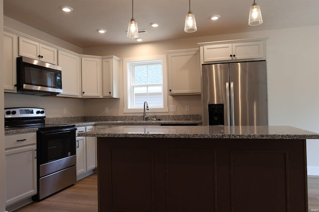 kitchen featuring a center island, recessed lighting, appliances with stainless steel finishes, wood finished floors, and white cabinetry