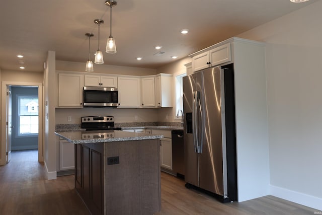 kitchen with pendant lighting, appliances with stainless steel finishes, white cabinetry, and a kitchen island