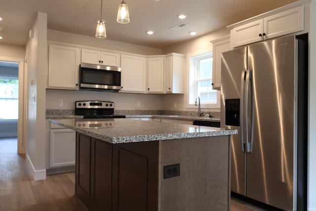 kitchen featuring appliances with stainless steel finishes, a kitchen island, dark wood-type flooring, and hanging light fixtures