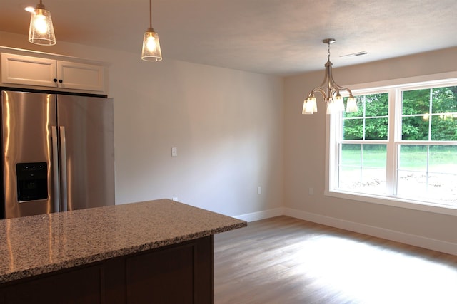 kitchen featuring a chandelier, light stone countertops, stainless steel refrigerator with ice dispenser, white cabinets, and light hardwood / wood-style floors