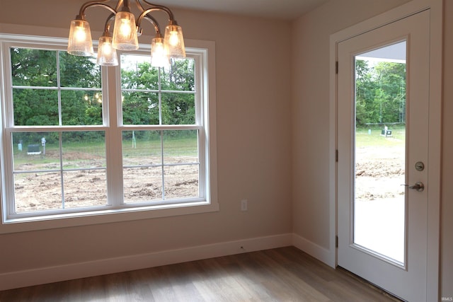 unfurnished dining area with hardwood / wood-style floors and an inviting chandelier