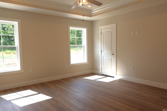 unfurnished room with ceiling fan, dark hardwood / wood-style floors, a raised ceiling, and ornamental molding