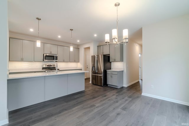 kitchen with appliances with stainless steel finishes, backsplash, pendant lighting, and dark hardwood / wood-style flooring