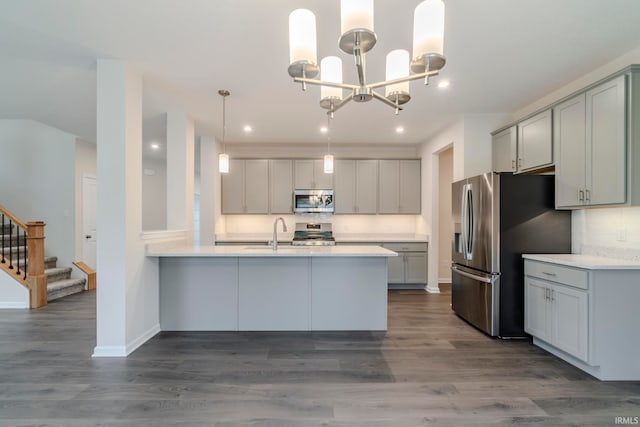 kitchen with tasteful backsplash, appliances with stainless steel finishes, decorative light fixtures, wood-type flooring, and a chandelier