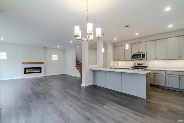 kitchen featuring hanging light fixtures, an inviting chandelier, dark hardwood / wood-style flooring, range, and backsplash