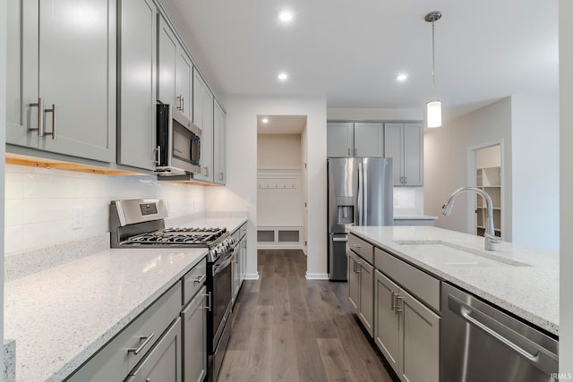 kitchen featuring hardwood / wood-style floors, backsplash, hanging light fixtures, sink, and appliances with stainless steel finishes