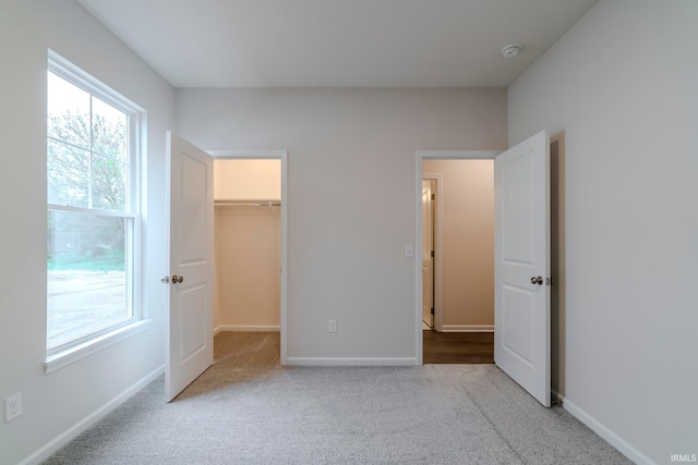 unfurnished bedroom featuring a walk in closet, a closet, and carpet