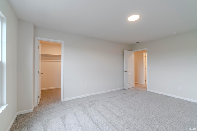 unfurnished bedroom with a walk in closet, carpet flooring, and a closet