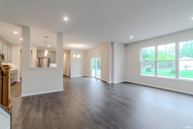 unfurnished living room featuring a chandelier and dark hardwood / wood-style flooring