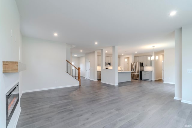 unfurnished living room with an inviting chandelier and hardwood / wood-style floors