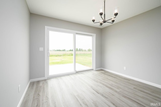 unfurnished room with light wood-type flooring and a chandelier