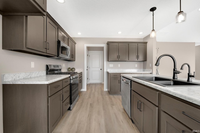 1016 Bryce Cir, Ligonier, IN 46767 - kitchen featuring stainless steel appliances, a sink, light wood-style floors, light countertops, and decorative light fixtures
