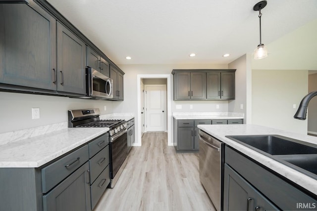 kitchen featuring sink, light hardwood / wood-style flooring, stainless steel appliances, gray cabinetry, and decorative light fixtures