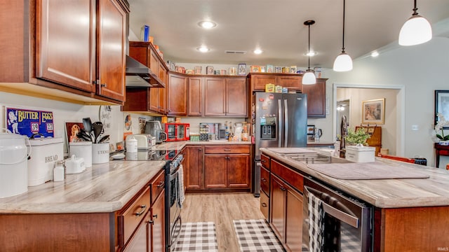 kitchen with decorative light fixtures, light wood-type flooring, wall chimney range hood, a kitchen island with sink, and appliances with stainless steel finishes