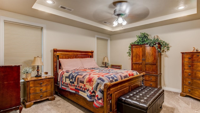 carpeted bedroom with ceiling fan and a tray ceiling