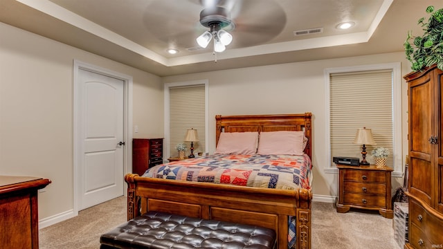 carpeted bedroom with ceiling fan and a tray ceiling