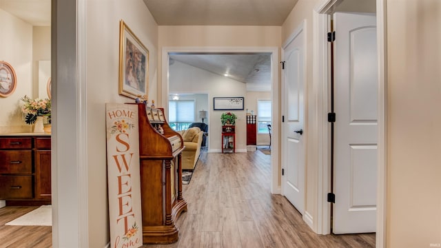 hall with light hardwood / wood-style flooring and lofted ceiling