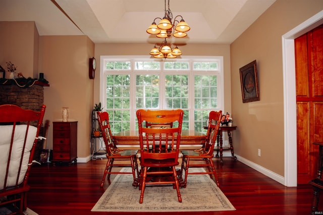 dining area with a raised ceiling, a chandelier, dark hardwood / wood-style floors, and a healthy amount of sunlight