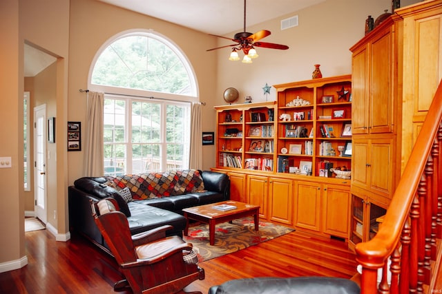 living room featuring a towering ceiling, a wealth of natural light, and hardwood / wood-style floors