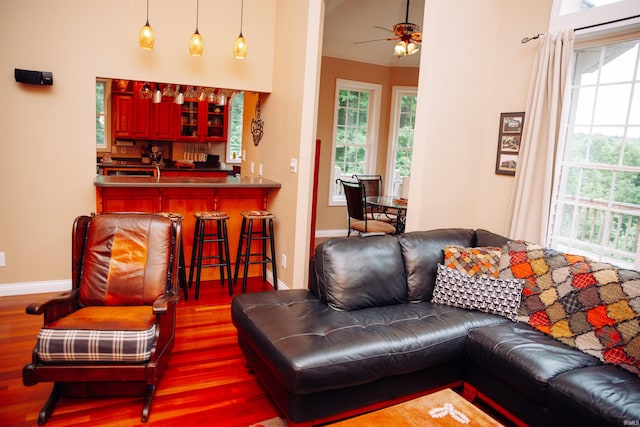 living room with bar area, ceiling fan, a healthy amount of sunlight, and hardwood / wood-style floors