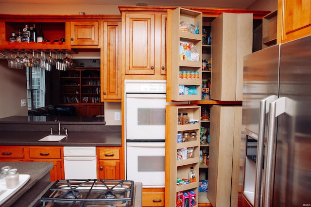 kitchen with stainless steel refrigerator with ice dispenser, sink, black gas stovetop, and double oven