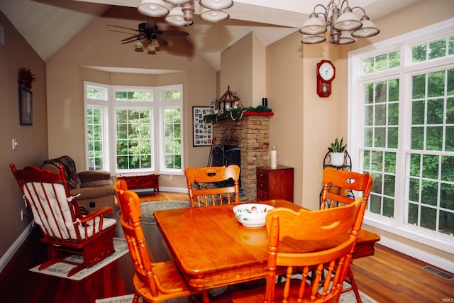 dining room featuring a healthy amount of sunlight, hardwood / wood-style flooring, a fireplace, and ceiling fan with notable chandelier