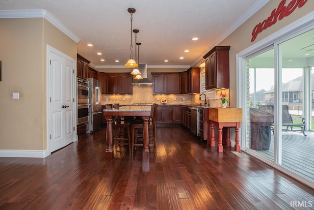 kitchen featuring wall chimney range hood, hanging light fixtures, dark hardwood / wood-style floors, light stone counters, and backsplash