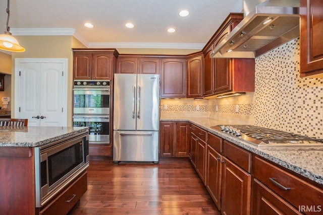 kitchen with dark hardwood / wood-style floors, hanging light fixtures, light stone counters, wall chimney range hood, and appliances with stainless steel finishes