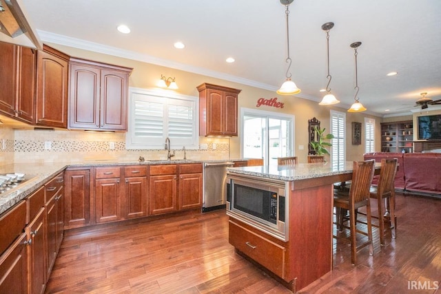 kitchen featuring backsplash, hardwood / wood-style flooring, a center island, appliances with stainless steel finishes, and sink