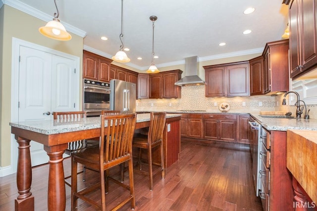 kitchen with a center island, appliances with stainless steel finishes, dark hardwood / wood-style floors, light stone counters, and wall chimney exhaust hood