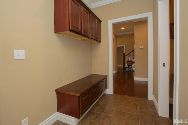 mudroom with ornamental molding and dark tile floors