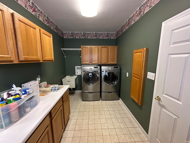 washroom with cabinets, a textured ceiling, light tile floors, and washing machine and dryer