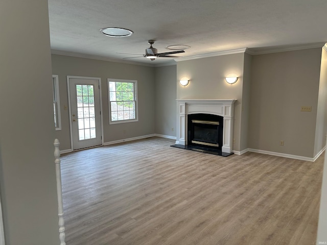 unfurnished living room with ceiling fan, a textured ceiling, light wood-type flooring, and ornamental molding