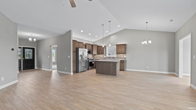 kitchen with light hardwood / wood-style floors, ceiling fan with notable chandelier, backsplash, a kitchen island, and appliances with stainless steel finishes