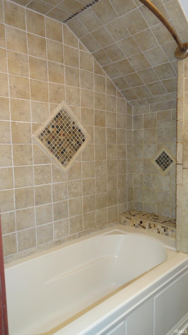 bathroom with lofted ceiling and tiled shower / bath