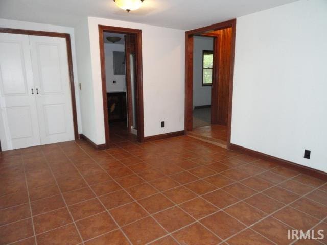 unfurnished bedroom featuring dark tile patterned floors and a closet