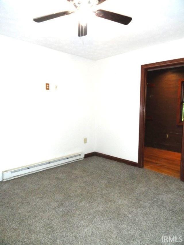 carpeted spare room with ceiling fan and a baseboard heating unit