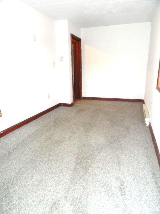 carpeted spare room featuring a textured ceiling and baseboard heating