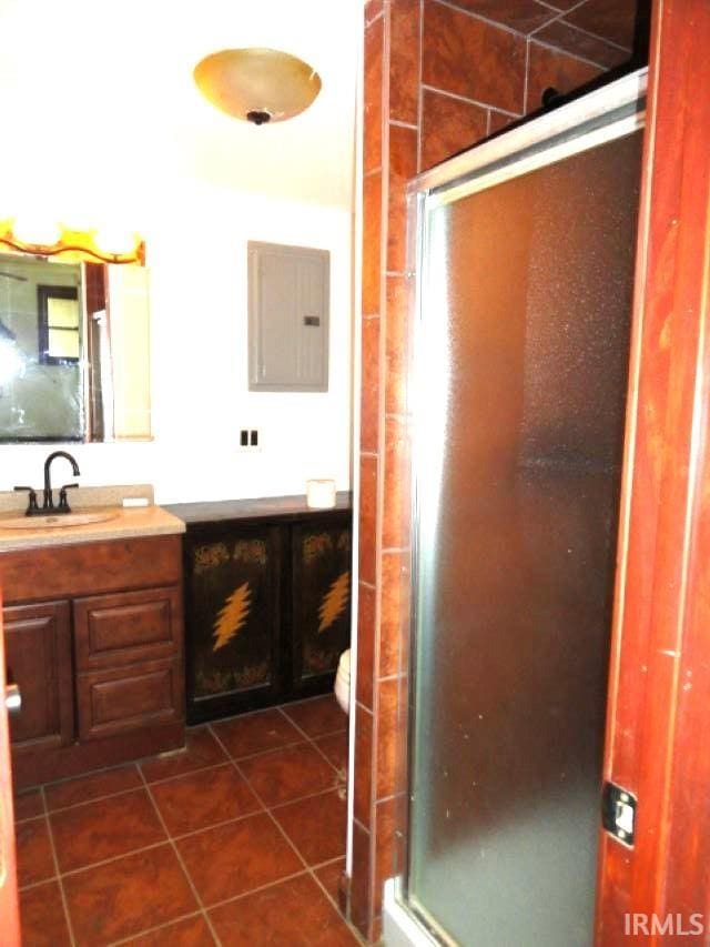 bathroom with tile patterned flooring, vanity, electric panel, and a shower with door