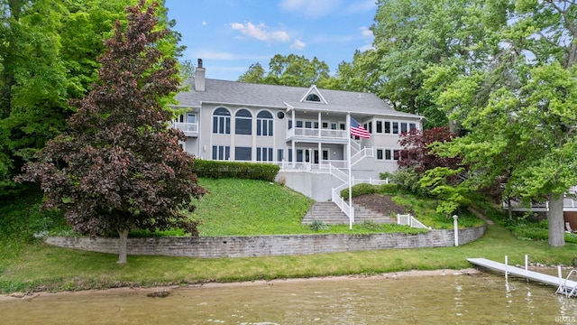 back of property with a lawn and a water view