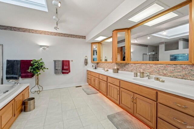 bathroom with double vanity, a skylight, tasteful backsplash, tile floors, and track lighting