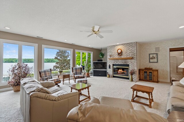 living room featuring a textured ceiling, brick wall, a fireplace, ceiling fan, and light colored carpet