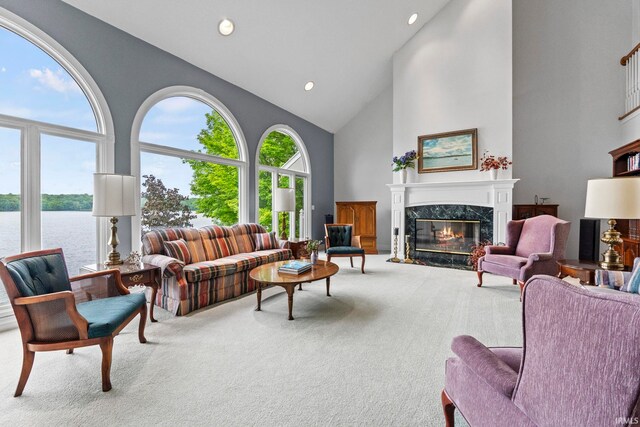 living room with high vaulted ceiling, a water view, carpet, and a high end fireplace