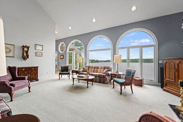 carpeted living room with a towering ceiling and a water view